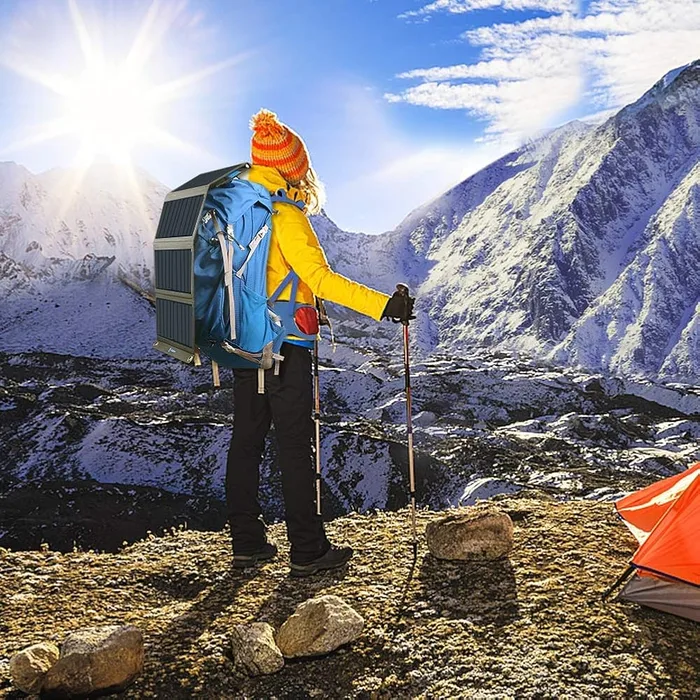 Panneau solaire BigBlue 28W sanglé sur un sac à dos de randonnée face à un massif enneigé