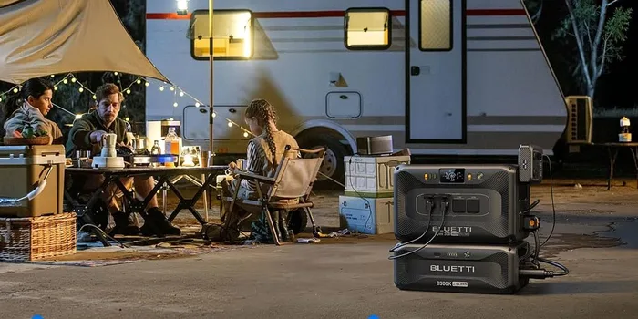 BLUETTI Apex 300 raccordée à un camping-car éclairé de nuit, sous un auvent