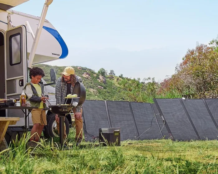 EcoFlow DELTA 2 Max et son panneau solaire 400 W déployés devant un camping-car, avec deux personnes préparant un repas