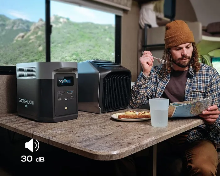 EcoFlow DELTA 2 Max posée sur une table dans un camping-car, à côté d'un occupant en train de lire
