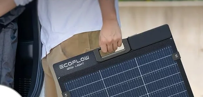 Panneau solaire EcoFlow 160W bifacial porté plié à la main devant un véhicule