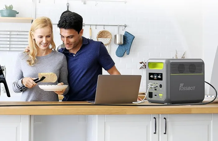 FOSSiBOT F1200 posée sur un îlot de cuisine, alimentant un ordinateur portable devant deux personnes