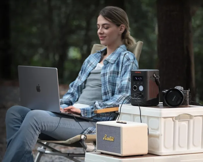Jackery Explorer 300D alimentant un ordinateur portable en forêt, posé sur une glacière