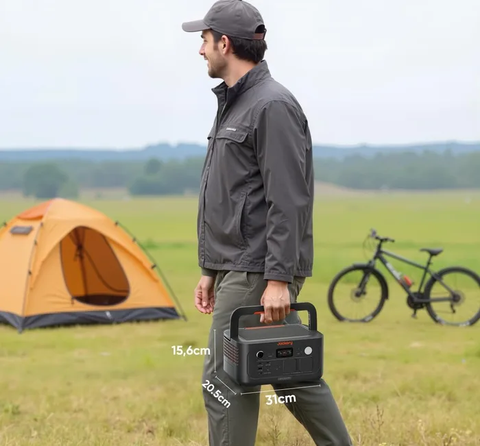 Jackery Explorer 500v2 transporté à la main en extérieur, à côté d'une tente et d'un vélo
