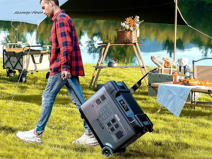 Oukitel P5000 Pro tractée sur ses roulettes dans l'herbe, devant un campement