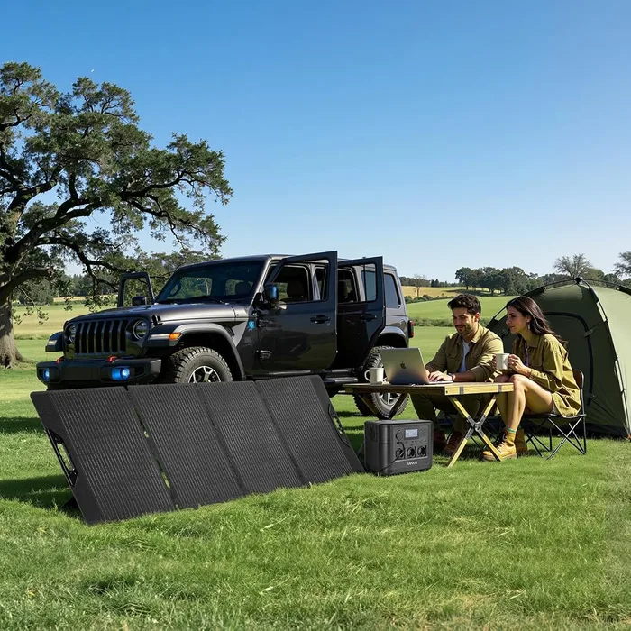 Station VEVOR M9 et son panneau solaire 200 W déployés devant un 4x4 et une tente, deux personnes attablées